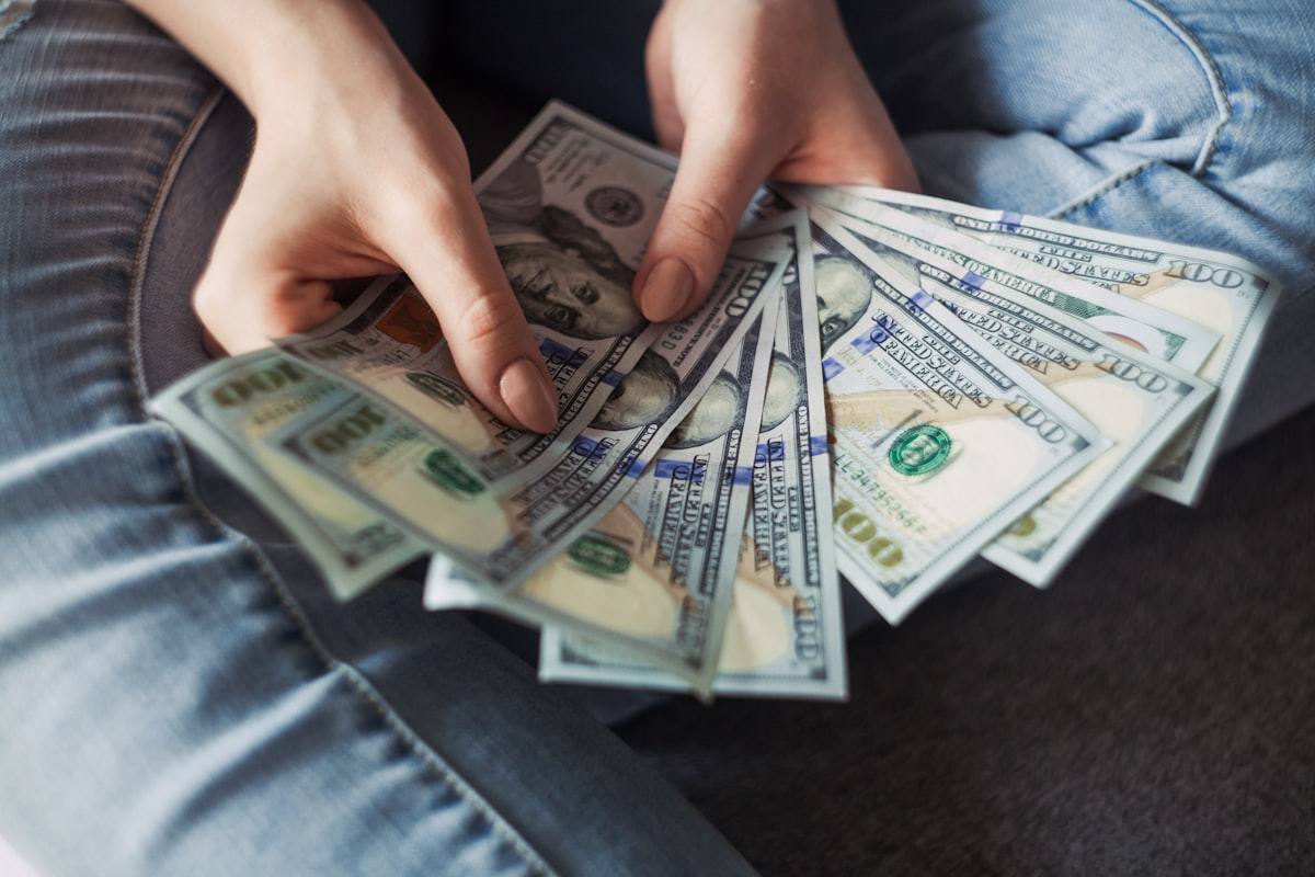 Tangan mengipaskan selembar uang sebagai ilustrasi bonus dan cashback